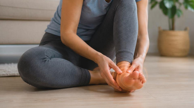 Woman experiencing vibrating sensation in foot while sitting indoors